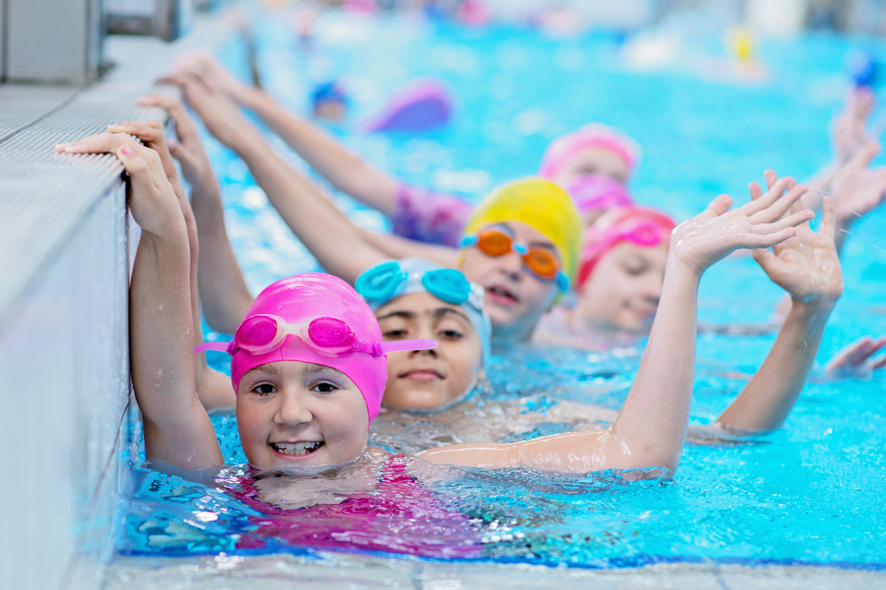 Happy Kids At The Swimming Pool. Young And Successful Swimmers Pose.