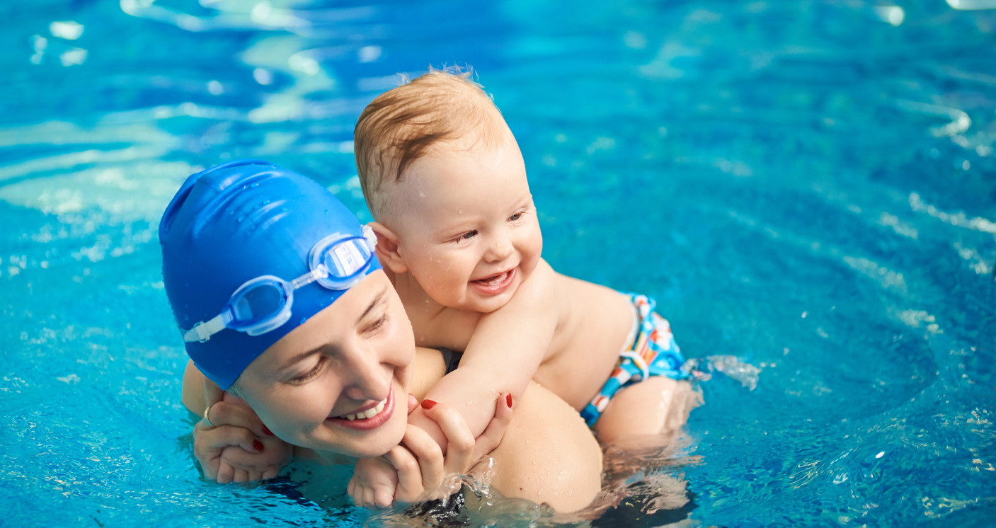 Child Having Fun In Water With Mom. Small Wet Boy Smiling Holging On His Mother's Back In Pool. Horizontal Portrait View