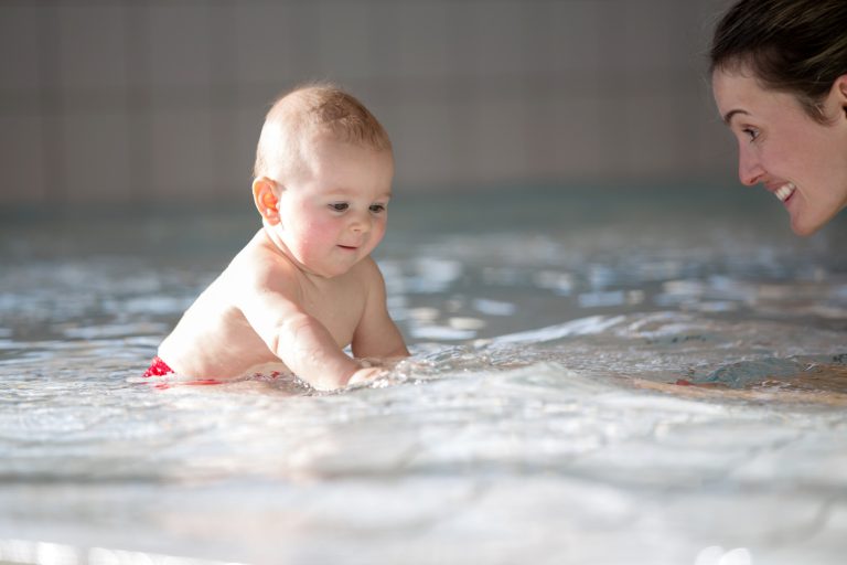 Little Cute Baby Boy, Swimming Happily In A Shallow Pool Water