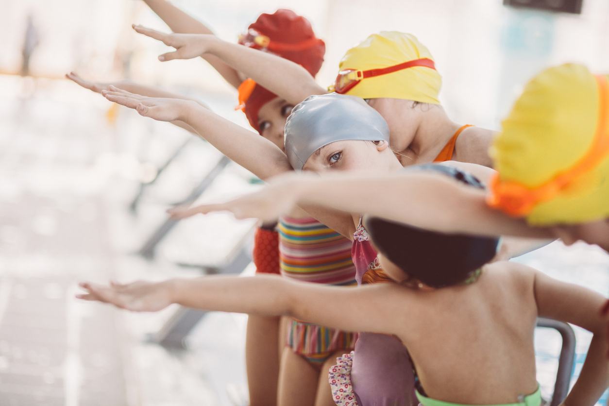 Instructor And Group Of Children Doing Exercises Near A Swimming Pool